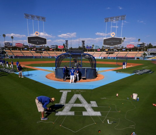 Un miembro del equipo de jardinería de los Dodgers de Los Ángeles pinta un logotipo en el campo antes de la práctica en preparación para el Juego 1 de una Serie Divisional de la Liga Nacional contra los Padres de San Diego, el jueves 3 de octubre de 2024, en Los Ángeles. (AP Foto/Mark J. Terrill)