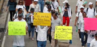 Manifestantes sostienen carteles en una marcha este sábado en San Salvador (El Salvador). Más de un millar de sindicalistas y miembros de organizaciones protestaron el sábado en las calles de la capital salvadoreña por los recortes propuestos por el Gobierno de Nayib Bukele para el presupuesto de Salud y Educación de 2025, que incluye la congelación de beneficios salariales y disminución de plazas. EFE/ Rodrigo Sura