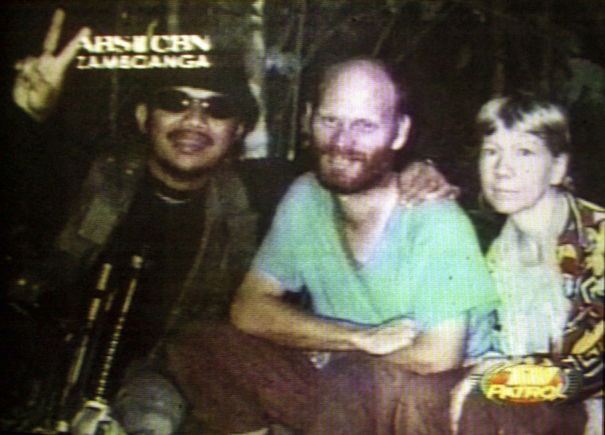 Martin, centro, y Gracia Burnham, derecha, ciudadanos estadounidenses que fueron secuestrados por el grupo filipino Abu Sayyaf, junto con su secuestrador Abu Sabaya, en esta foto tomada de video y difundida el 10 de octubre del 2001. (ABS CBN via AP)