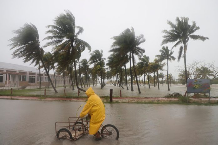 Una persona monta su bicicleta a través de una calle inundada mientras el huracán Milton, en México. (AP Foto/Martin Zetina)