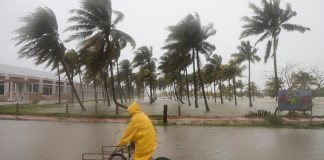 Una persona monta su bicicleta a través de una calle inundada mientras el huracán Milton, en México. (AP Foto/Martin Zetina)