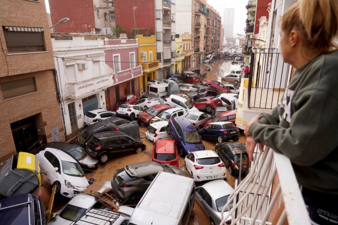 Una mujer mira por su balcón a los vehículos atrapados en la calle durante una inundación en Valencia, el miércoles 30 de octubre de 2024. (AP Foto/Alberto Saiz)