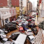 Una mujer mira por su balcón a los vehículos atrapados en la calle durante una inundación en Valencia, el miércoles 30 de octubre de 2024. (AP Foto/Alberto Saiz)