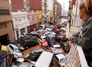 Una mujer mira por su balcón a los vehículos atrapados en la calle durante una inundación en Valencia, el miércoles 30 de octubre de 2024. (AP Foto/Alberto Saiz)