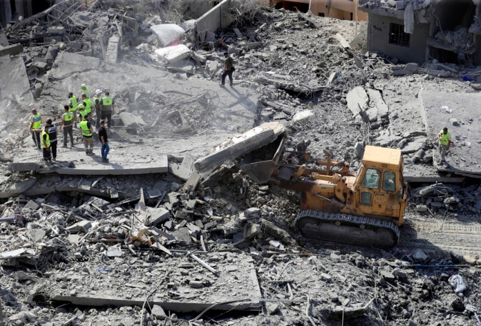 Rescatistas utilizan una excavadora para retirar escombros de edificios derruidos mientras buscan víctimas en un lugar golpeado por ataques israelíes en la localidad de Qana, en el sur de Líbano, el miércoles 16 de octubre de 2024. (AP Foto/Mohammed Zaatari)