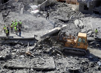 Rescatistas utilizan una excavadora para retirar escombros de edificios derruidos mientras buscan víctimas en un lugar golpeado por ataques israelíes en la localidad de Qana, en el sur de Líbano, el miércoles 16 de octubre de 2024. (AP Foto/Mohammed Zaatari)