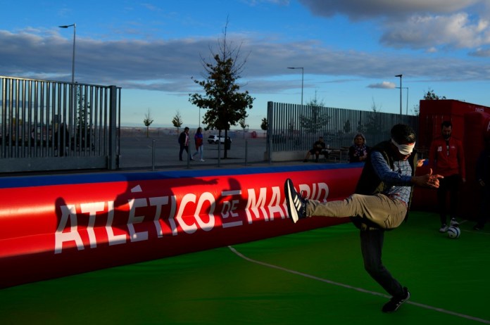 Un aficionado trata de patear a ciegas un balón antes del partido de la Liga de Campeones entre el Atlético de Madrid y el Lille en el Estadio Metropolitano, el miércoles 23 de octubre de 2024 (AP Foto/Manu Fernández)