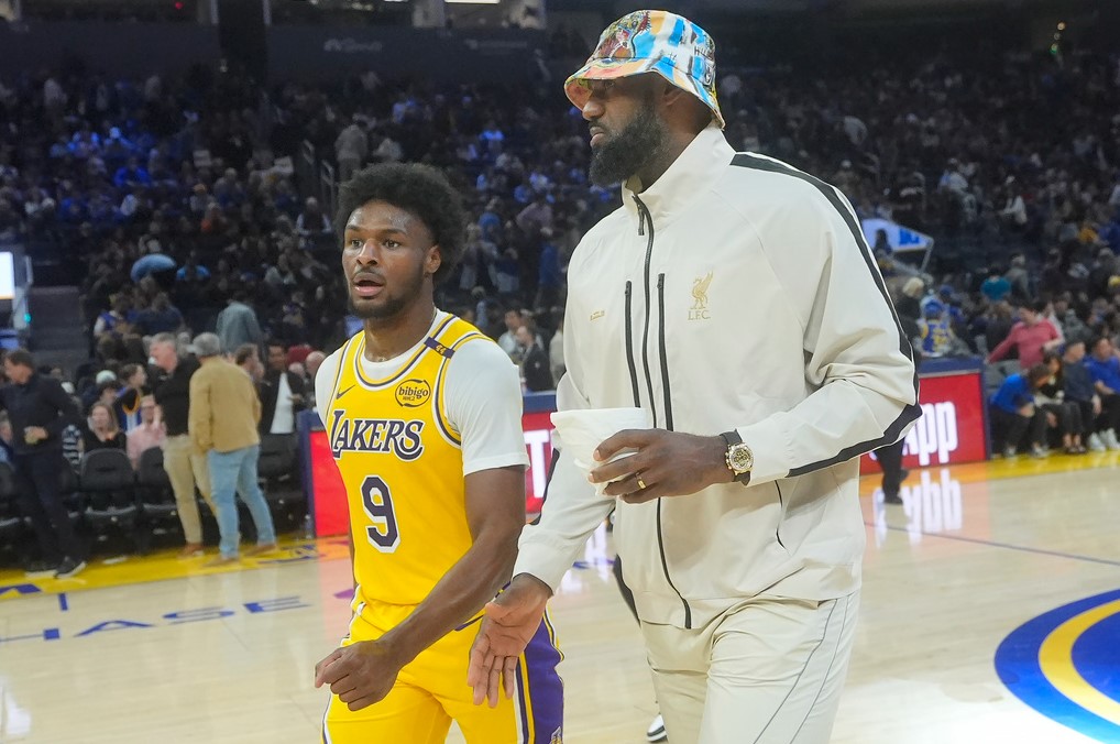 El escolta de los Lakers de Los Ángeles, Bronny James (9), sale de la cancha con LeBron James durante el medio tiempo de un partido de baloncesto de pretemporada de la NBA contra los Warriors de Golden State en San Francisco, el viernes 18 de octubre de 2024. (AP Foto/Jeff Chiu)