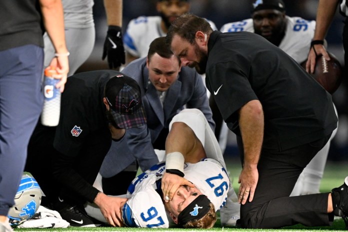 Aidan Hutchinson (97), defensive end de los Lions de Detroit, es atendido por el personal médico del equipo después de sufrir una lesión, aparentemente una fractura, durante la segunda mitad del juego de la NFL en contra de los Cowboys de Dallas, el domingo 13 de octubre de 2024, en Arlington, Texas. (AP Foto/Jerome Miron)