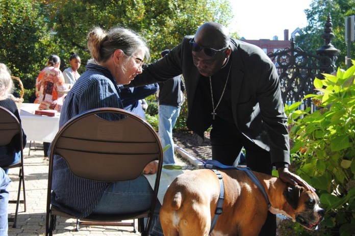 El reverendo Jean Beniste, un inmigrante haitiano, bendice a un perro y a su propietaria, el sábado 5 de octubre de 2024, durante el evento de Bendición de Animales en el jardín de la Iglesia Episcopal St. Paul de Concord, Nueva Hampshire. (G. Jeffrey MacDonald vía AP)