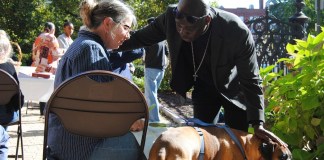 El reverendo Jean Beniste, un inmigrante haitiano, bendice a un perro y a su propietaria, el sábado 5 de octubre de 2024, durante el evento de Bendición de Animales en el jardín de la Iglesia Episcopal St. Paul de Concord, Nueva Hampshire. (G. Jeffrey MacDonald vía AP)