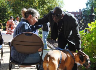 El reverendo Jean Beniste, un inmigrante haitiano, bendice a un perro y a su propietaria, el sábado 5 de octubre de 2024, durante el evento de Bendición de Animales en el jardín de la Iglesia Episcopal St. Paul de Concord, Nueva Hampshire. (G. Jeffrey MacDonald vía AP)