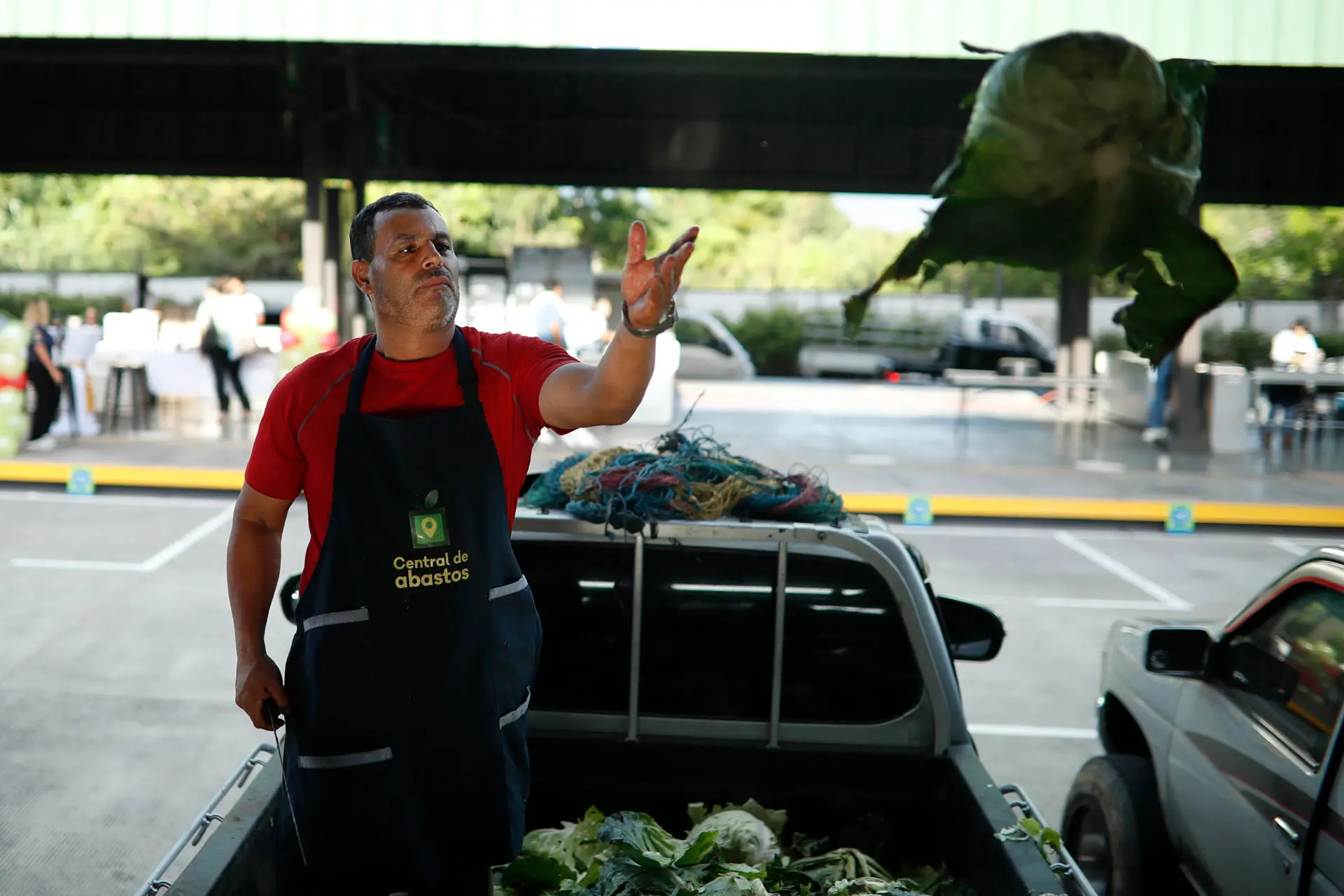 AME3038. SAN SALVADOR (EL SALVADOR), 30/10/2024.- Un vendedor de repollos lanza uno en una central de abastos habilitada por el Gobierno, este miércoles, en Soyapango (El Salvador). Una central de abasto de frutas, verduras y otros productos 