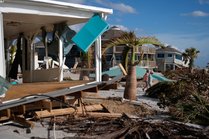 Kery Flynn, a la derecha, y su amigo caminan frente a una casa dañada con el techo destruido tras el paso del huracán Milton, el 13 de octubre de 2024, en Manasota Key, en Englewood, Florida. (AP Foto/Rebecca Blackwell, Archivo)