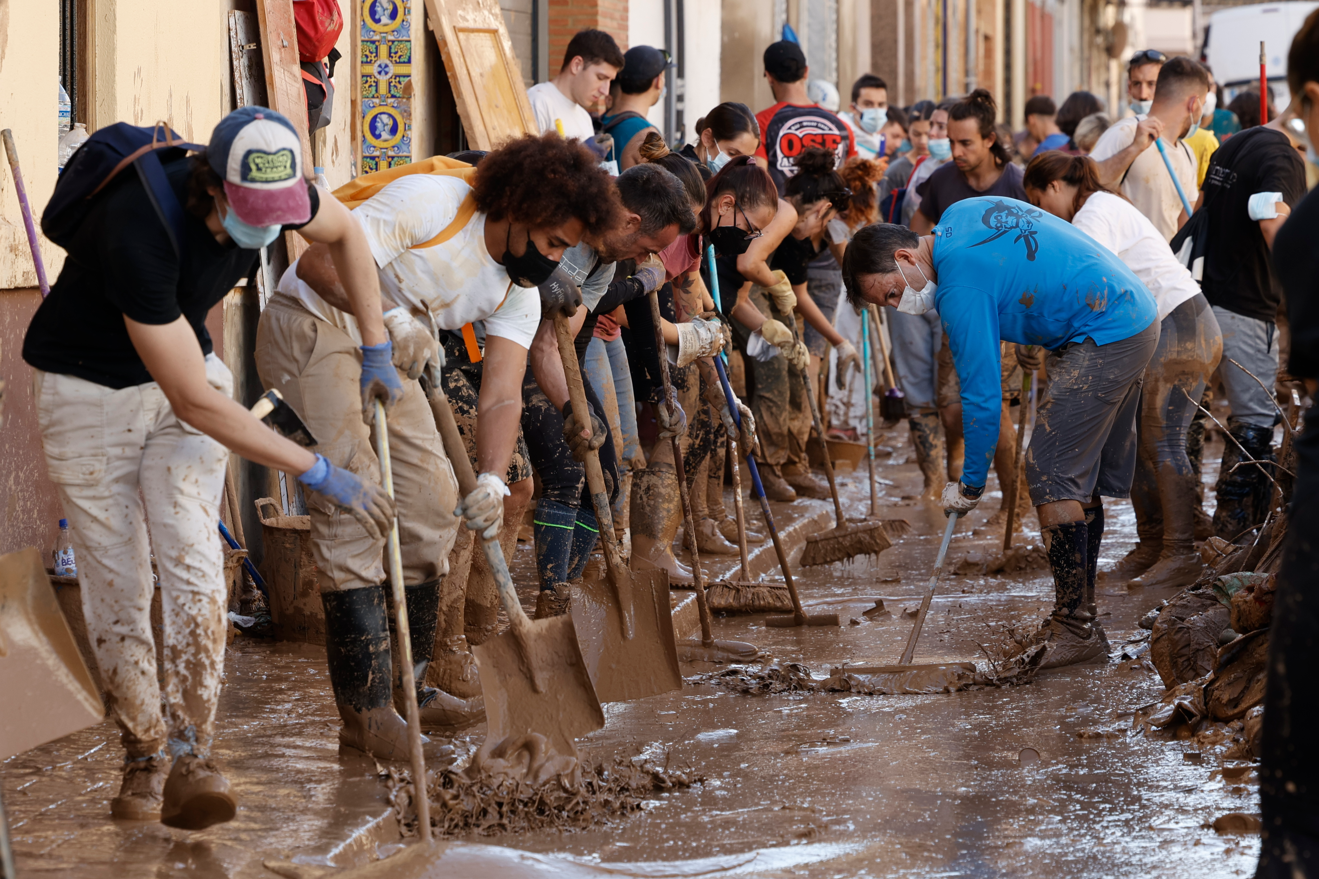 Varias personas retiran el lodo acumulado en una calle de la localidad valenciana de Paiporta, este sábado. Foto La Hora: EFE/ Biel Aliño