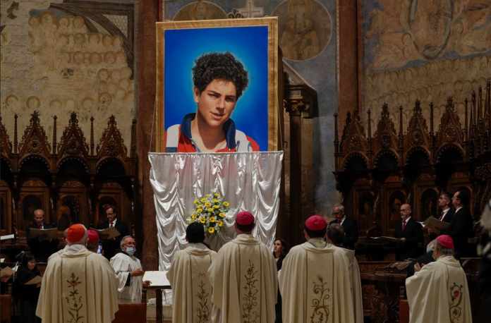 Una imagen de Carlo Acutis, un joven italiano de 15 años que murió en 2006 de leucemia, es descubierta durante su ceremonia de beatificación celebrada por el cardenal Agostino Vallini en la Basílica de San Francisco, en Asís, Italia, el sábado 10 de octubre de 2020.