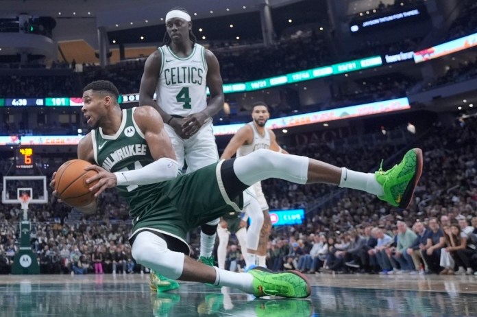 Giannis Antetokounmpo, de los Bucks de Milwaukee, cae a la duela frente a Jrue Holiday, de los Celtics de Boston, durante la segunda mitad del juego de baloncesto de la NBA, el domingo 10 de noviembre de 2024, en Milwaukee. (AP Foto/Morry Gash)