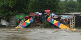 Varias personas paradas frente a un puente peatonal colapsado el sábado 16 de noviembre de 2024 debido a las inundaciones causadas por las lluvias que ha provocado el paso de la tormenta tropical Sara en San Pedro Sula, Honduras.Foto: La Hora/AP