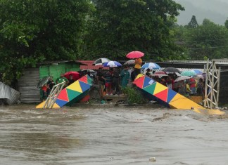 Varias personas paradas frente a un puente peatonal colapsado el sábado 16 de noviembre de 2024 debido a las inundaciones causadas por las lluvias que ha provocado el paso de la tormenta tropical Sara en San Pedro Sula, Honduras.Foto: La Hora/AP