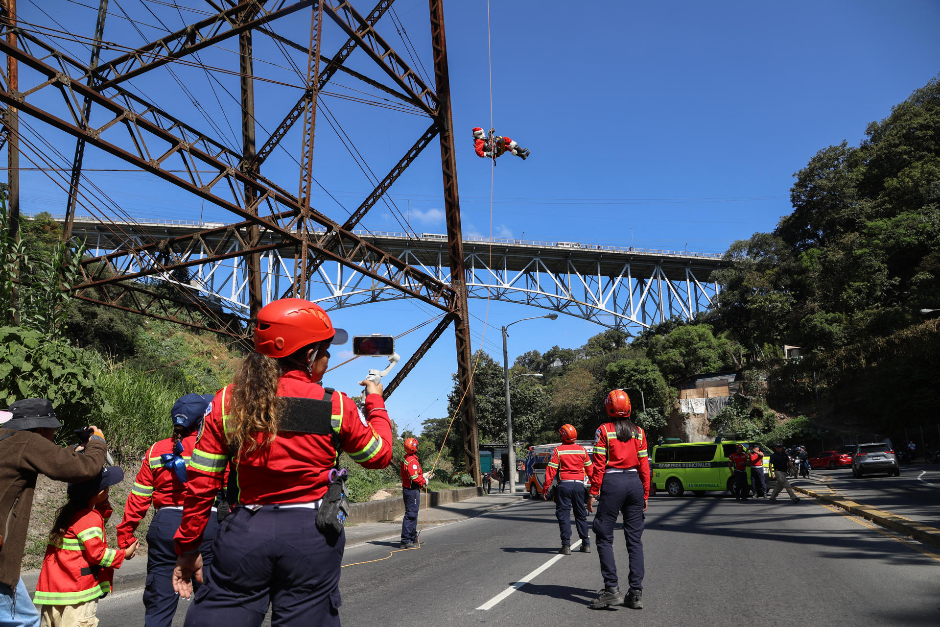 El Mayor Héctor Chacón Cuellar (c-arriba), miembro del Cuerpo de Bomberos Municipales de la Ciudad de Guatemala, realizó su tradicional salto del Puente las Vacas, vestido como Papá Noel, para llevarle regalos a niños de escasos recursos este domingo, en Ciudad de Guatemala (Guatemala). EFE/ Mariano Macz.