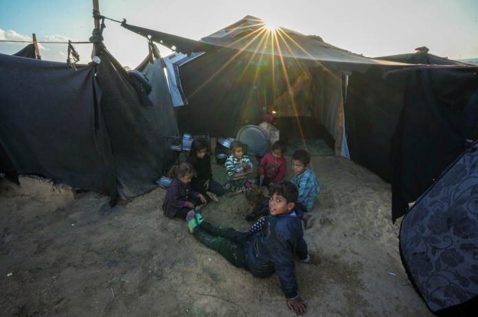 Los nietos de Reda Abu Zarada, desplazado de Jabaliya, en el norte de Gaza, juegan junto a su tienda de campaña en un campamento en Khan Younis, Franja de Gaza, el jueves 19 de diciembre de 2024. (Foto AP/Abdel Kareem Hana)