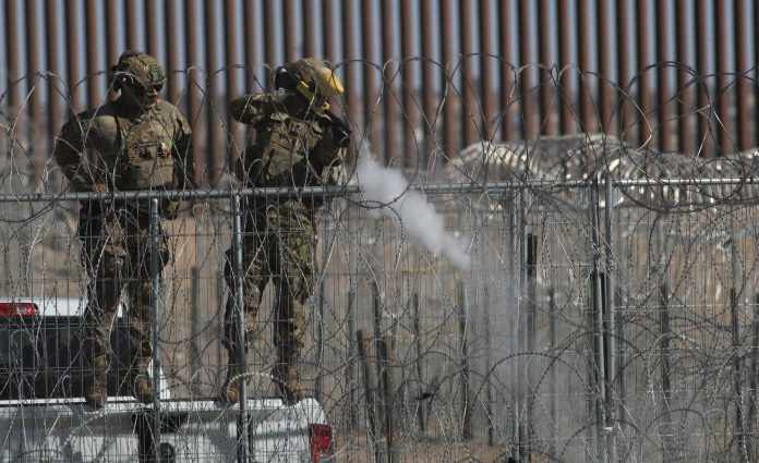 Un integrante de la Guardia Nacional de Texas dispara bolas de pimienta para dispersar a un grupo de migrantes este miércoles, en ciudad Juárez, Chihuahua (México).