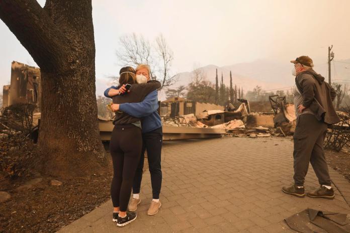 Altadena (United States), 09/01/2025.- Melissa Young (C) gets a hug from a neighbor while looking through the remains of her home that was destroyed by the Eaton wildfire with her brother Mark Mosher (R) in the Altadena, California, USA, 09 January 2025. According to the California Governor's office, more than 7,500 firefighting and emergency personnel are involved in response efforts, as multiple wildfires are continuing to burn across Southern California, destroying many homes and businesses, and forcing nearly two hundred thousand residents to evacuate in the Los Angeles area. (incendio forestal) EFE/EPA/ALLISON DINNER