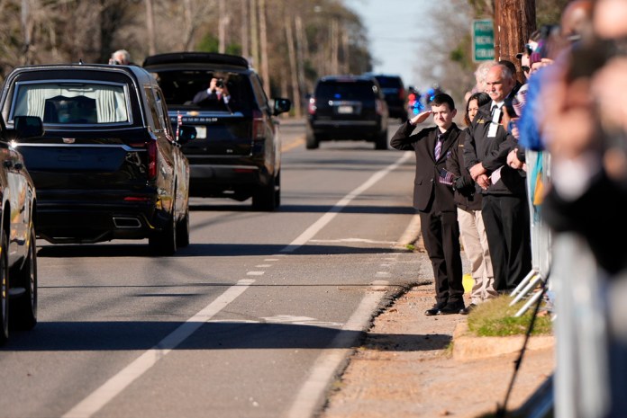 Un niño saluda al coche fúnebre que transporta el ataúd del expresidente Jimmy Carter.