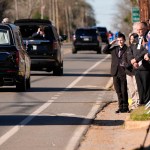 Un niño saluda al coche fúnebre que transporta el ataúd del expresidente Jimmy Carter.