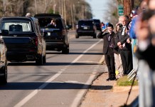 Un niño saluda al coche fúnebre que transporta el ataúd del expresidente Jimmy Carter.