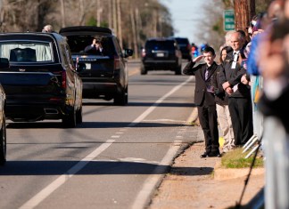 Un niño saluda al coche fúnebre que transporta el ataúd del expresidente Jimmy Carter.