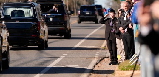 Un niño saluda al coche fúnebre que transporta el ataúd del expresidente Jimmy Carter.