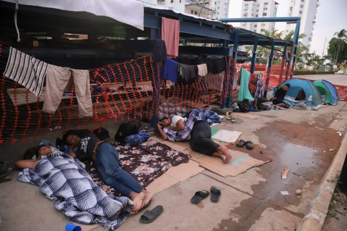 Migrantes durmiendo en un lado de una calle de Acapulco.