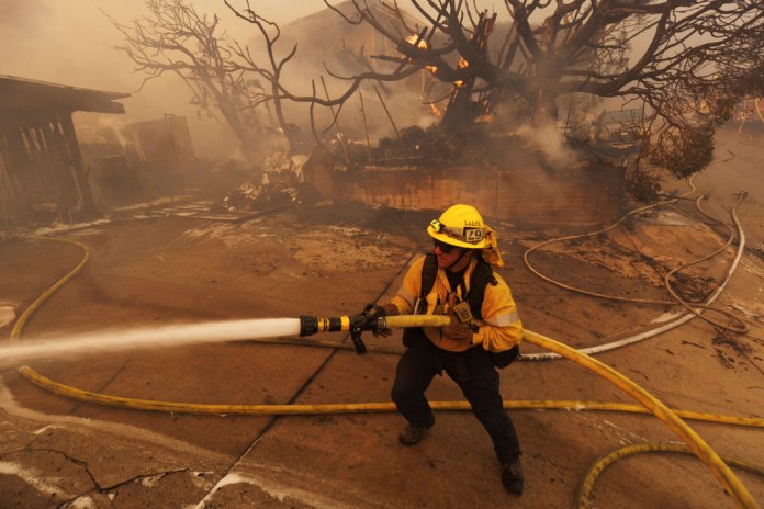 Un bombero sofoca las llamas del incendio Palisades frente a una residencia en el vecindario Pacific Palisades de Los Ángeles.