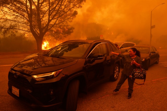 Una mujer llora mientras intenta huir del incendio de Palisades que avanza por las calles del mismo barrio.