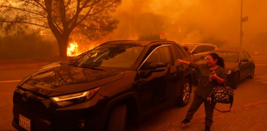 Una mujer llora mientras intenta huir del incendio de Palisades que avanza por las calles del mismo barrio.