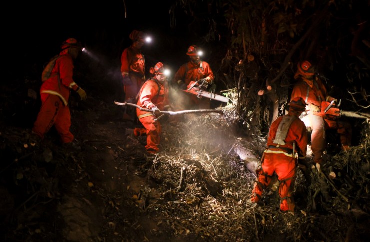 Un equipo de trabajo del Departamento de Correccionales de California trabaja en las líneas de contención para combatir el incendio Palisades