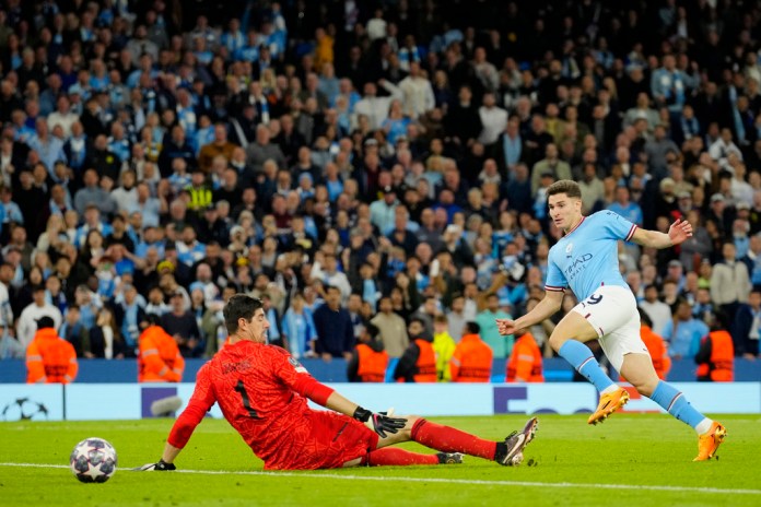 Julián Álvarez del Manchester City anota el cuarto gol de su equipo ante el portero del Real Madrid Thibaut Courtois durante el partido de vuelta de las semifinales de la Liga de Campeones entre el Manchester City y el Real Madrid en el estadio Etihad en Manchester, Inglaterra, el miércoles 17 de mayo de 2023. Foto La Hora: AP