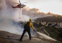 Los bomberos del condado de Los Ángeles utilizan mangueras y lanzan agua desde un helicóptero para combatir el incendio forestal de Palisades en Pacific Palisades, California, (EE.UU.). EFE/CAROLINE BREHMAN