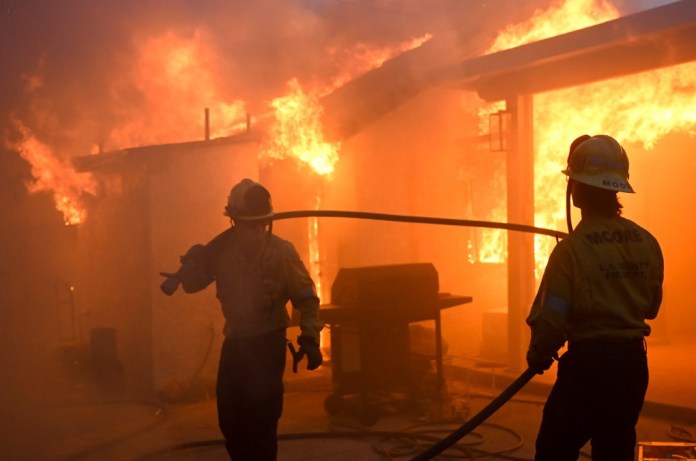 Dos bomberos luchan contra el incendio Eaton, que arrasa con varias construcciones en Altadena, California, el miércoles 8 de enero de 2025