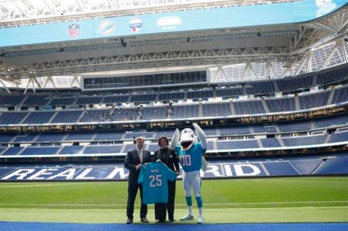 Brett Gosper, director de la NFL en Europa y Asia-Pacífico y Pri Shumate, vicepresidenta de los Miami Dolphins, en el césped del estadio Santiago Bernabéu con la mascota del equipo, durante el acto celebrado este viernes en Madrid. Foto La Hora: EFE