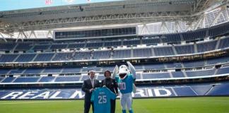 Brett Gosper, director de la NFL en Europa y Asia-Pacífico y Pri Shumate, vicepresidenta de los Miami Dolphins, en el césped del estadio Santiago Bernabéu con la mascota del equipo, durante el acto celebrado este viernes en Madrid. Foto La Hora: EFE