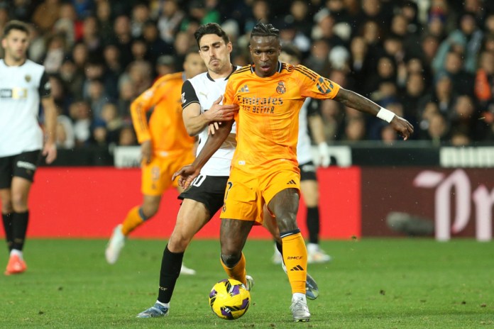 Vinicius Junior, del Real Madrid, al frente, y Andre Almeida, del Valencia, luchan por el balón durante un partido de fútbol de la Liga española en el estadio Mestalla en Valencia, España, el viernes 3 de enero de 2025 Foto La Hora: AP