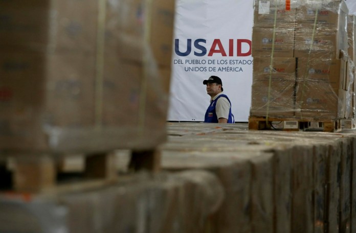 Un hombre pasa frente a cajas de ayuda humanitaria de USAID