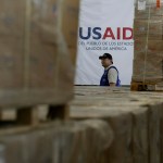 Un hombre pasa frente a cajas de ayuda humanitaria de USAID