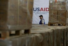 Un hombre pasa frente a cajas de ayuda humanitaria de USAID