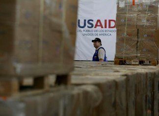 Un hombre pasa frente a cajas de ayuda humanitaria de USAID