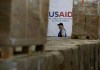 Un hombre pasa frente a cajas de ayuda humanitaria de USAID