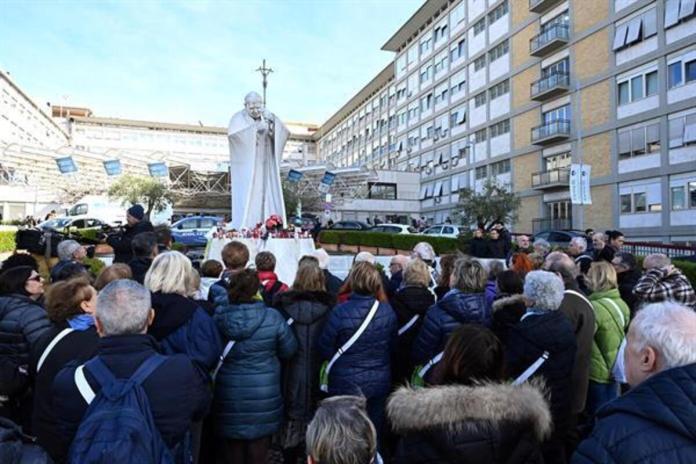 Fieles rezan por el papa Francisco ante la estatua del Papa San Juan Pablo II frente al Hospital Universitario Gemelli, donde está hospitalizado, en Roma, el 26 de febrero de 2025. Foto La Hora: EFE