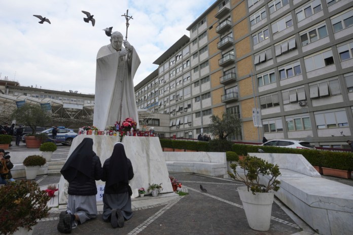 Dos monjas rezan frente a una estatua de san Juan Pablo II frente al hospital policlínico Agostino Gemelli, en Roma. Foto La Hora: AP